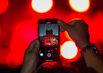 pantalla de móvil entre las manos  de una persona que graba evento en el Patio de condeduque