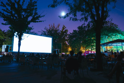 pantalla de cine de verano iluminada, foto nocturna, gente sentada en el patio de butacas